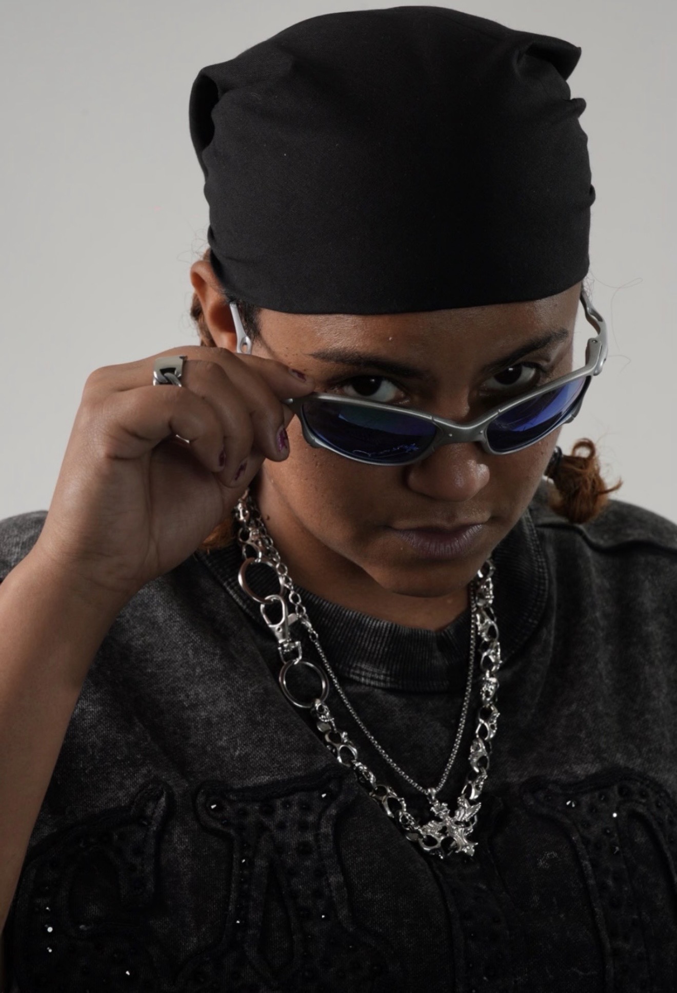 Michy Mata, Dominican artist, lowering her sunglasses in a black durag and chrome chains